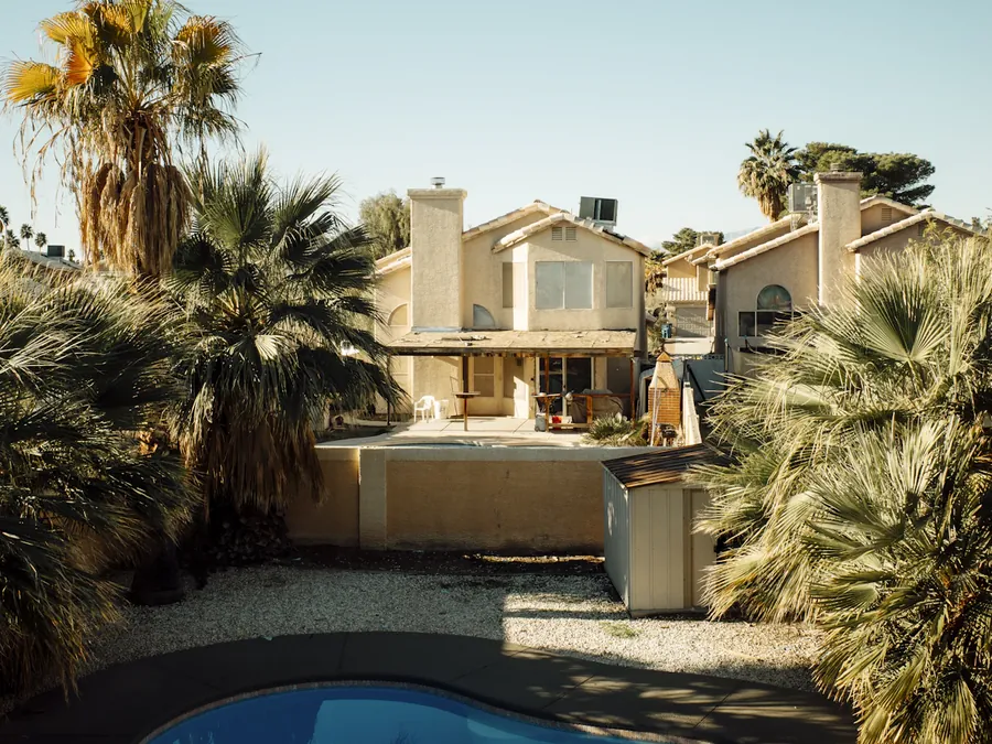 A backyard pool below a stucco-finished block rear wall with a pilaster, the kind of perimeter wall that often serves as a pool fence in Queen Creek